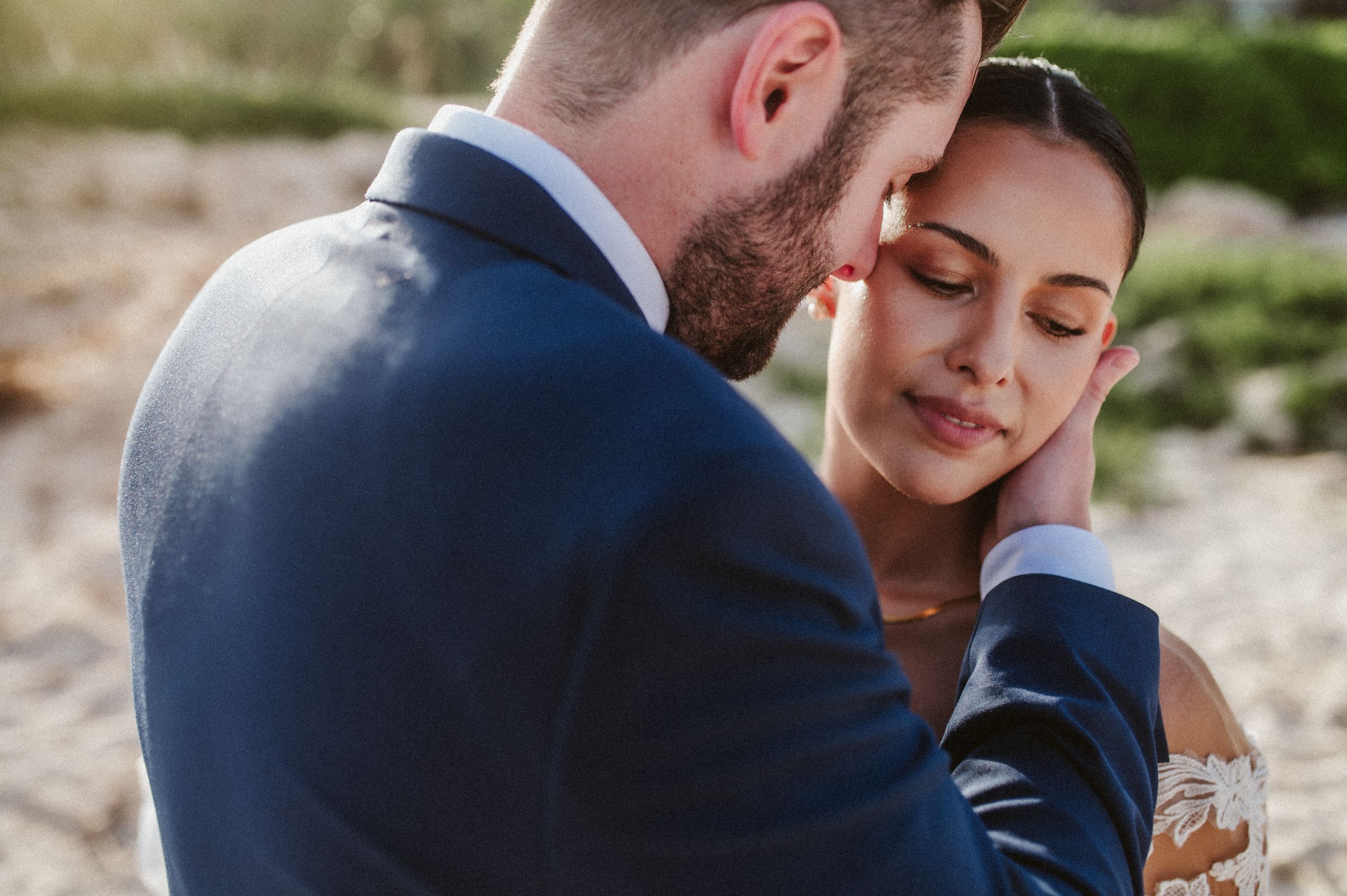 A tender moment between newlyweds sharing an intimate embrace outdoors during their wedding photoshoot.