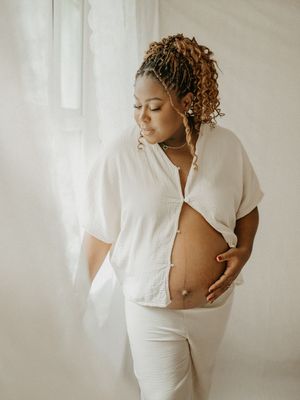 Artistic maternity photo series in white showing a pregnant woman in flowing fabric against a light neutral background.