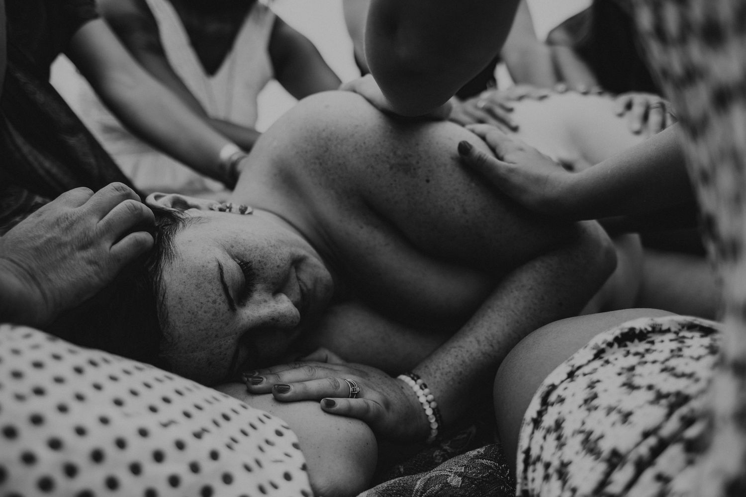 foto preto e branco, mulher deitada em ritual de cura com varias mãos sobre ela em circulo feminino em  Portugal
