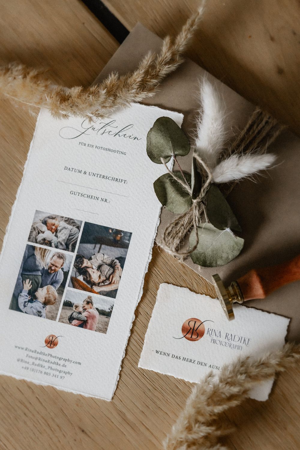 Wedding invitation suite with photo collage and dried floral elements on wooden table.