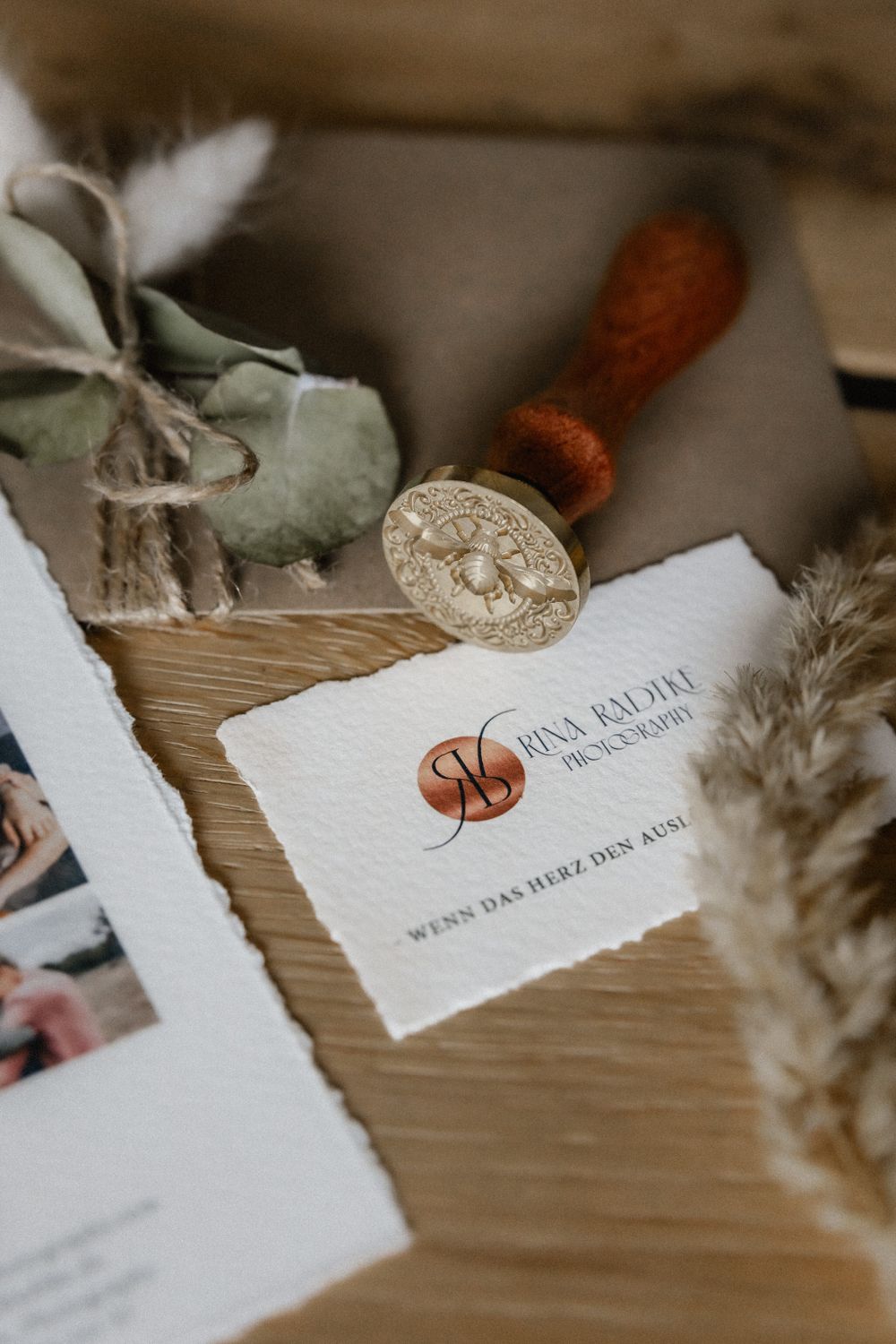 Wedding stationery with deckled edges and wax seal displayed on wooden surface.
