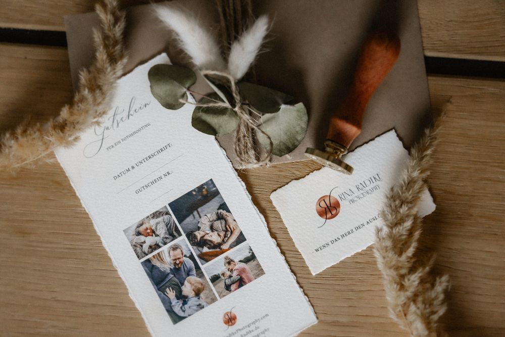 Wedding invitation cards with photo layouts and deckled edges arranged on wooden surface.