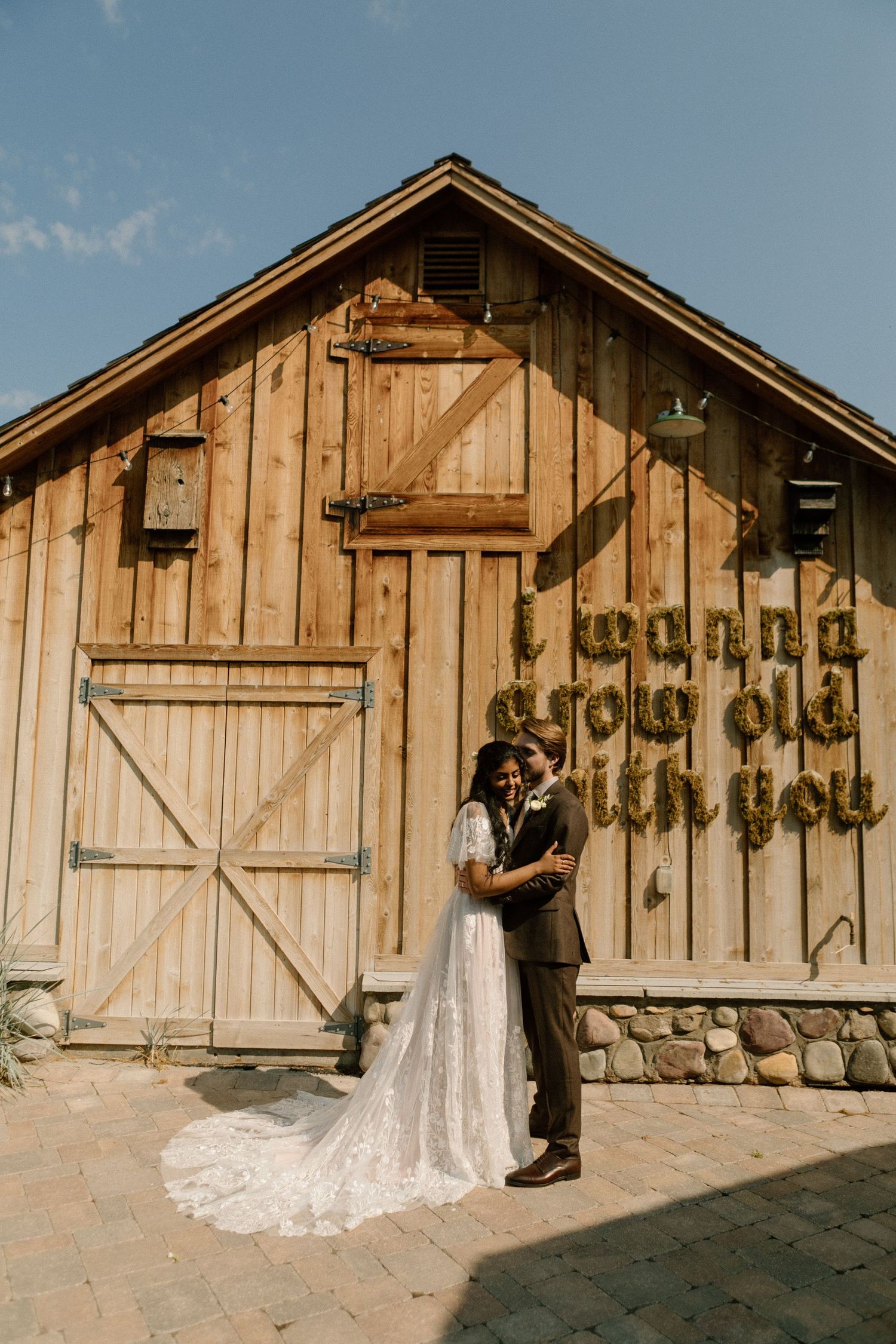 Rustic wooden barn exterior with large doors and decorative elements serves as wedding venue backdrop.