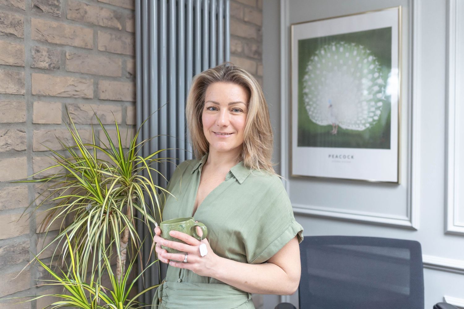 Belief coding therapist holding a cup of coffee during a home personal branding shoot, exuding a relaxed and welcoming vibe.