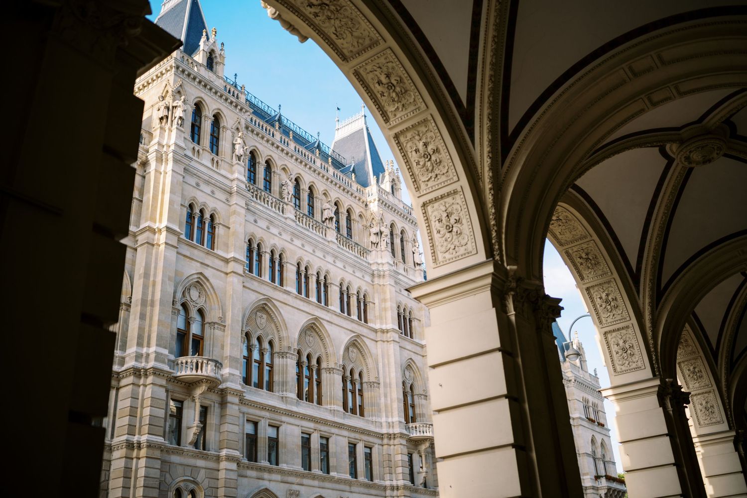Gothic architecture detail of Vienna City Hall viewed through arched colonnade in Austria.