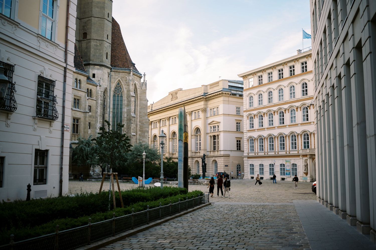 Historic cobblestone courtyard with classical buildings and green umbrellas in Vienna's city center.