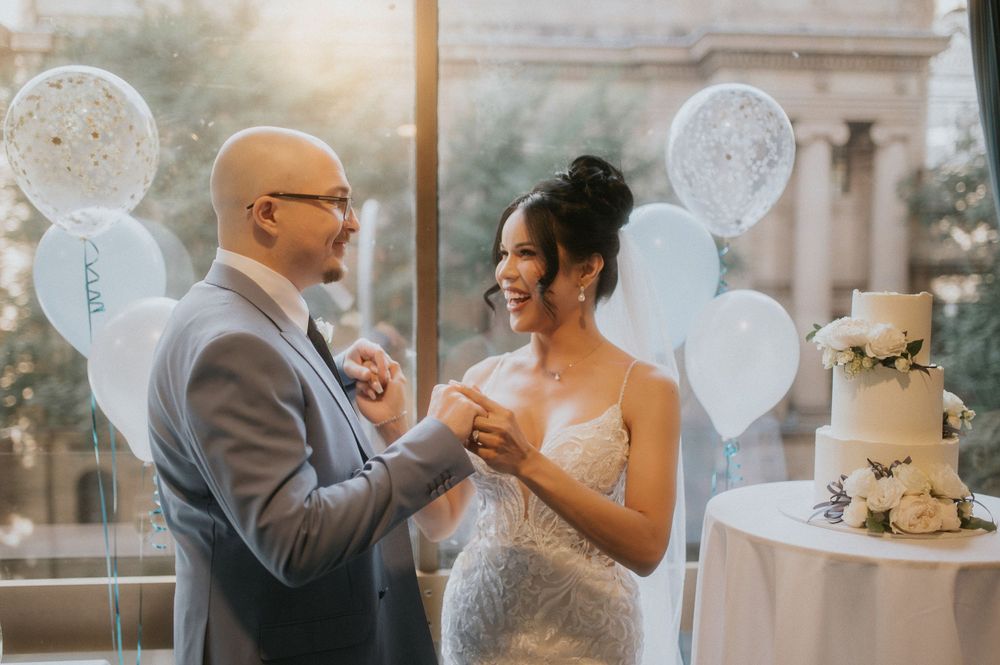 Wedding celebration with white balloons and cake in elegant venue setting.