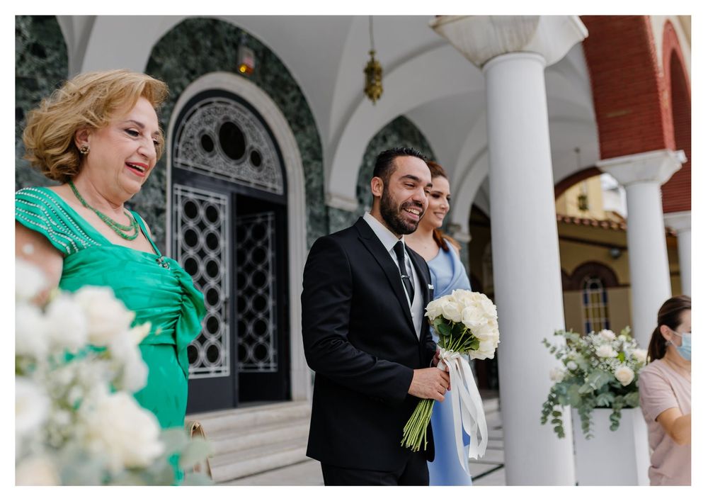 A couple celebrating outside a grand church entrance with white floral decorations and elegant columns.