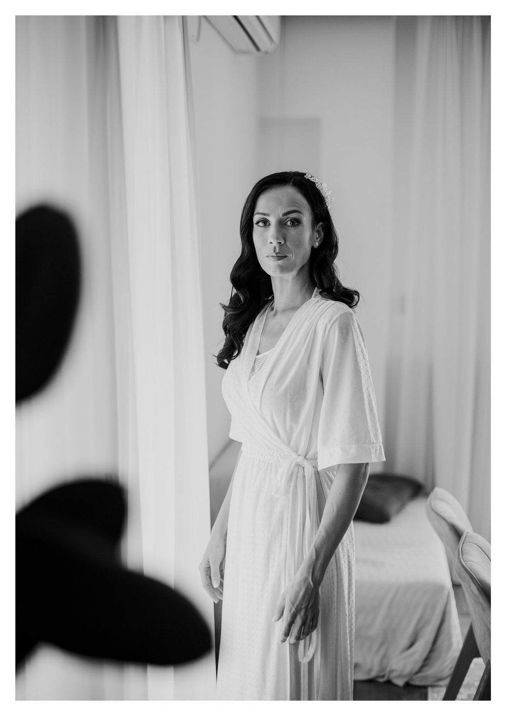 Black and white portrait of a bride in a flowing white robe preparing for her wedding day.