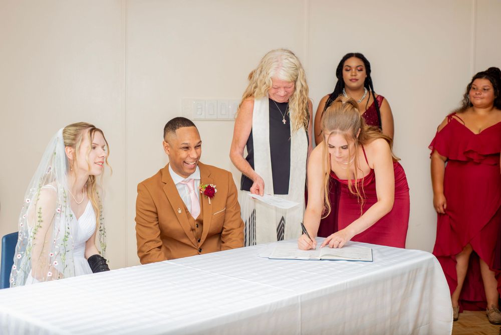 A group gathers around a table during a wedding ceremony signing.
