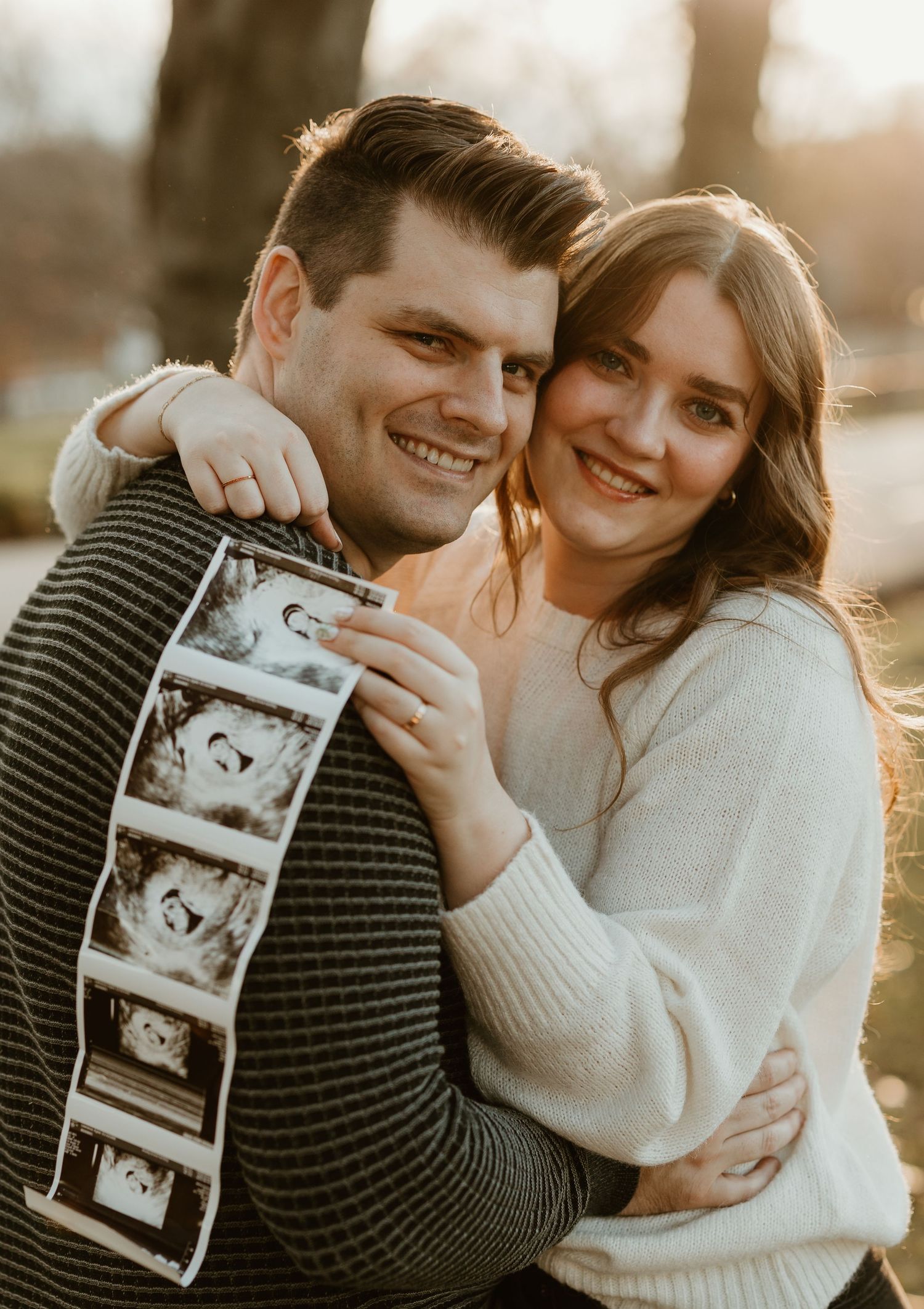 Happy couple showing off ultrasound photos during a pregnancy announcement photoshoot.