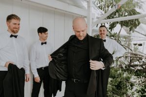 Group preparing formal attire indoors with white architectural details.