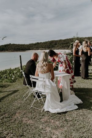 Wedding ceremony signing at waterfront location with decorative table setup.