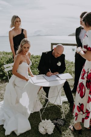 Marriage license signing ceremony at outdoor waterfront location.
