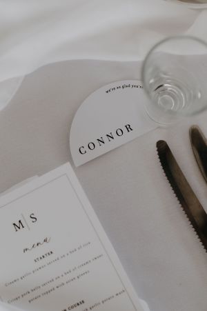 Minimalist wedding place setting with name card and menu in elegant black and white design.