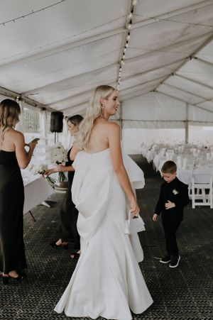 Wedding reception scene under a white tent with string lights and elegant decor.