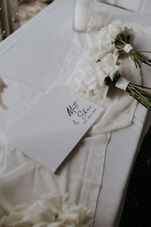 White wedding card and bouquet arrangement on light colored fabric.