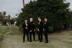Wedding party members in formal attire stand together outdoors for portrait.