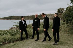 Groomsmen walking along coastal path during wedding photoshoot.
