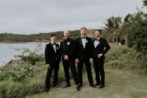 Wedding party members pose together at tropical oceanside location.