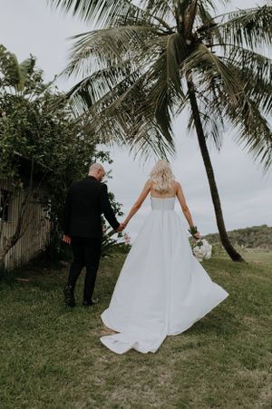 Romantic wedding portrait under palm tree with flowing white dress.