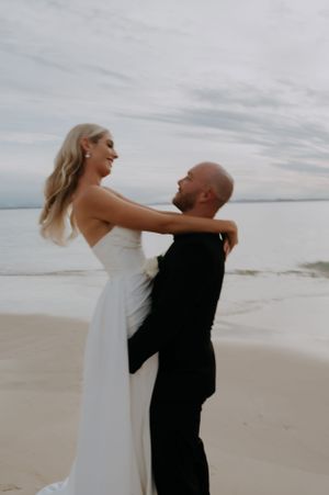 A joyful couple shares a romantic moment during their beach wedding photoshoot.