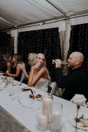 Guests enjoying drinks at an evening wedding reception with sparkling fairy lights in the background.