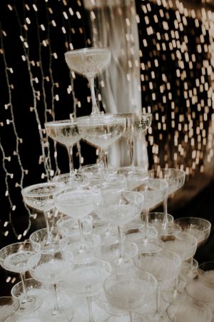 A tower of elegant champagne coupe glasses stacked in layers for a wedding celebration.
