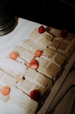 Small square wedding cake pieces decorated with fresh strawberries on a white surface.