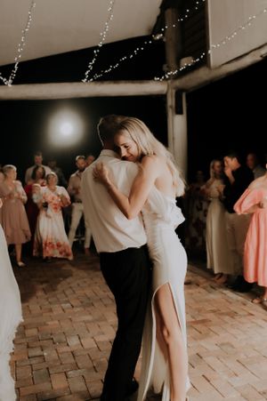 A romantic dance on a brick patio under twinkling string lights at an evening reception.