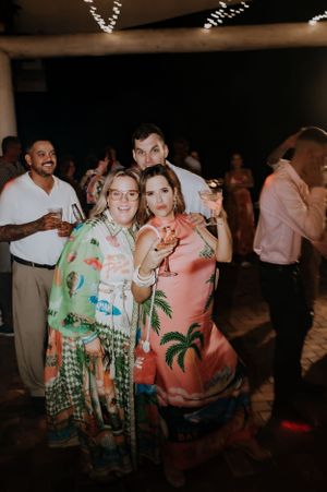Wedding guests in tropical attire enjoying the reception dance party under string lights.