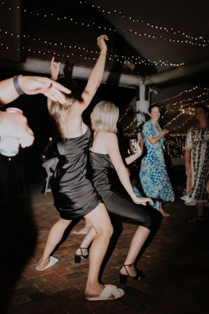 Wedding guests dancing enthusiastically under string lights at an evening reception.