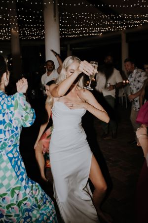 A joyful dance celebration under string lights at an evening wedding reception.