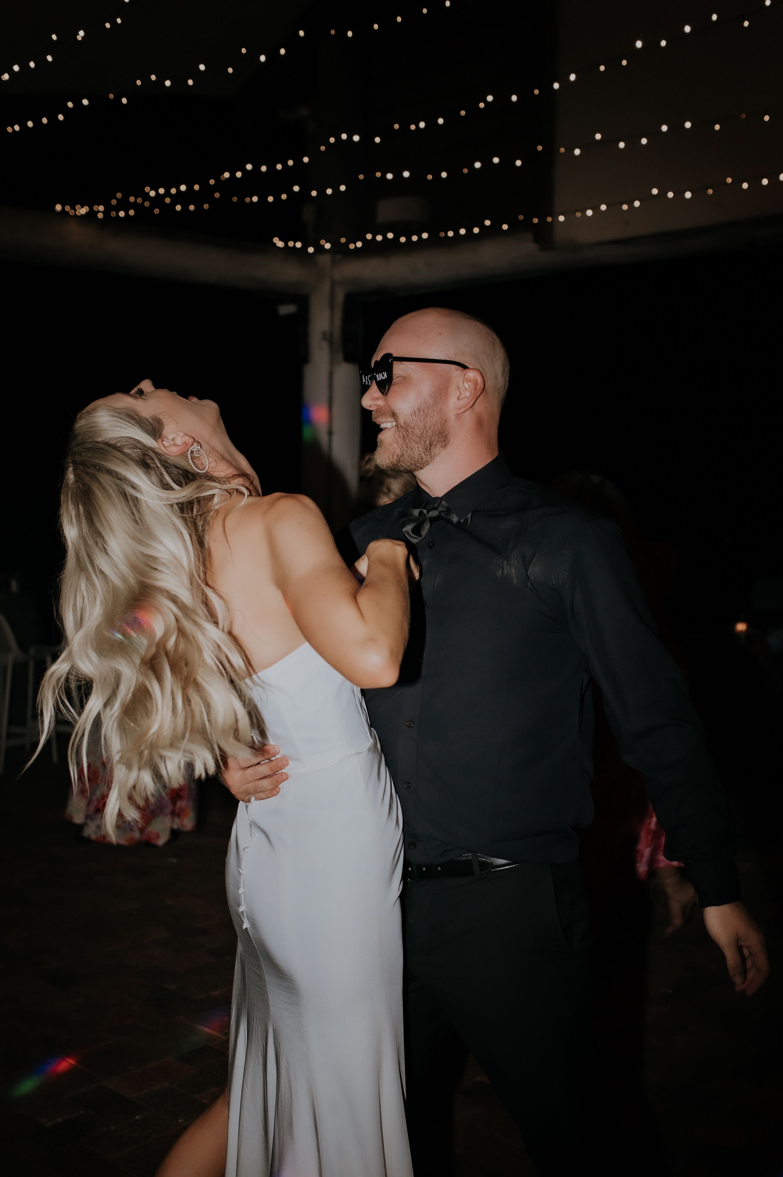 Couple sharing an intimate dance moment under sparkling overhead lights.