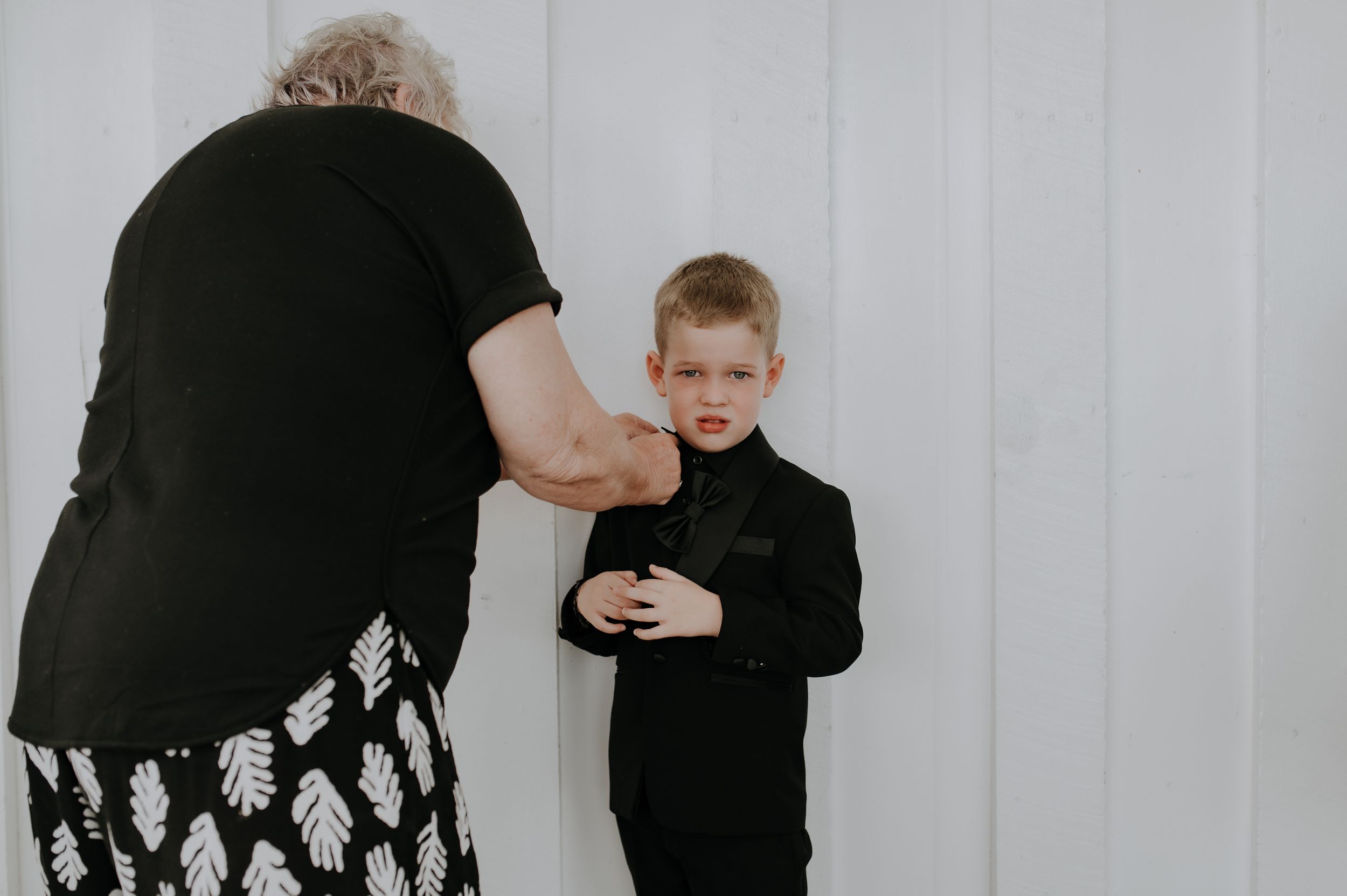 Black formal wear being adjusted against white background.