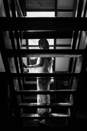 Dramatic black and white view through staircase slats of wedding preparation.