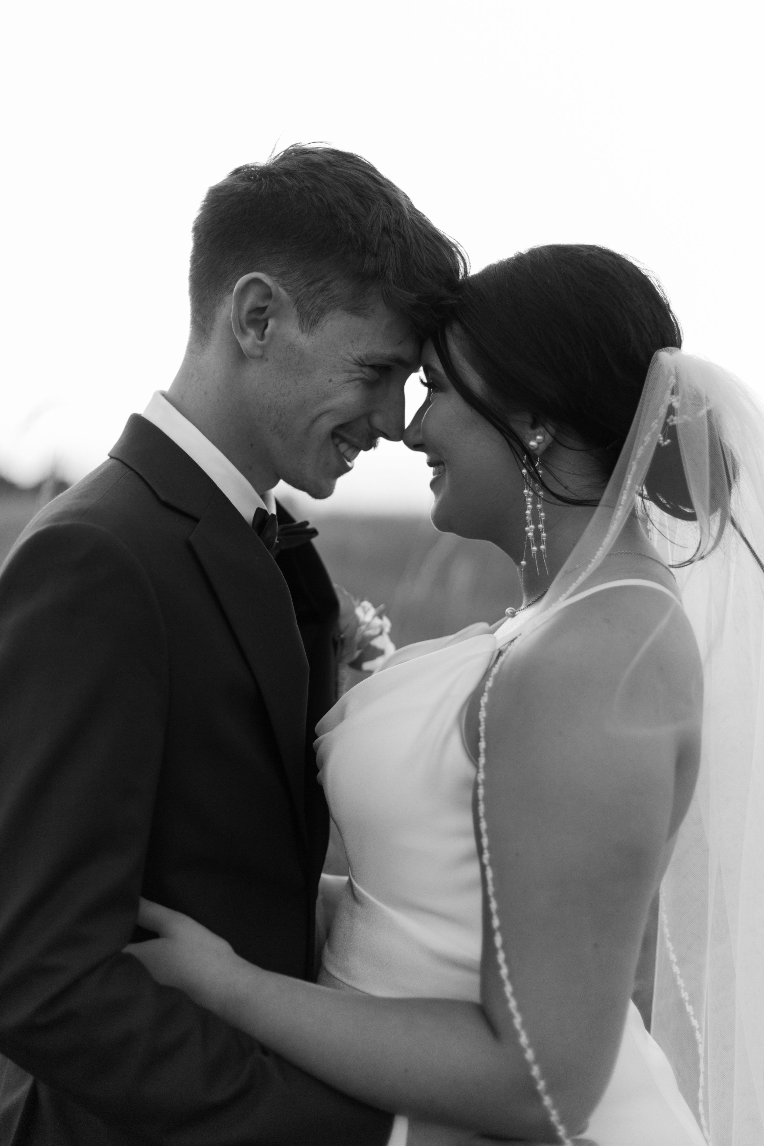 Black and white portrait of bride and groom sharing tender moment.
