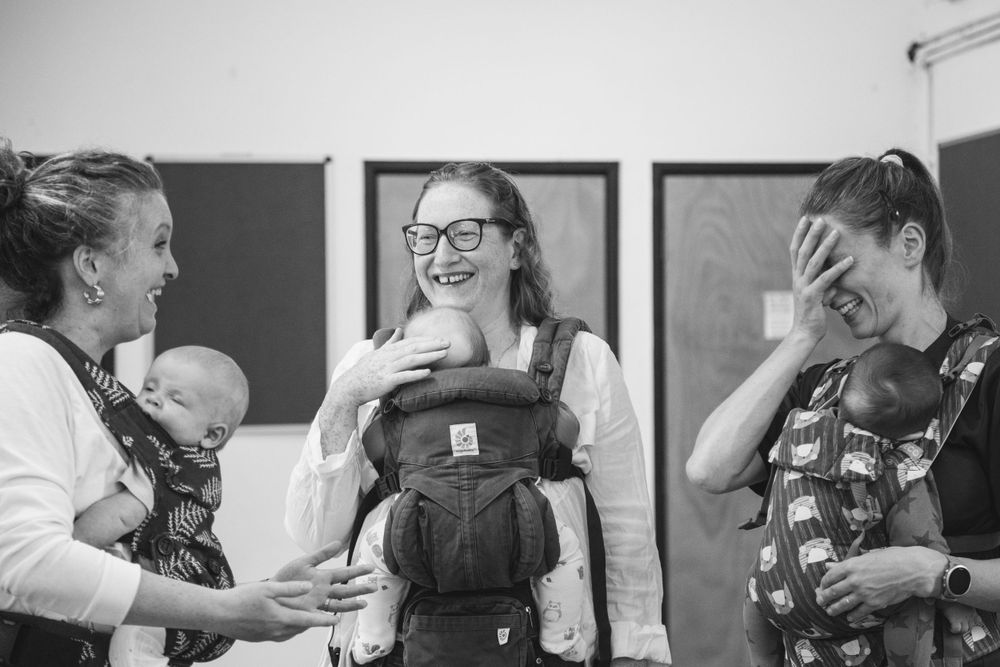 A joyful group gathering showing support and connection during a babywearing meet.