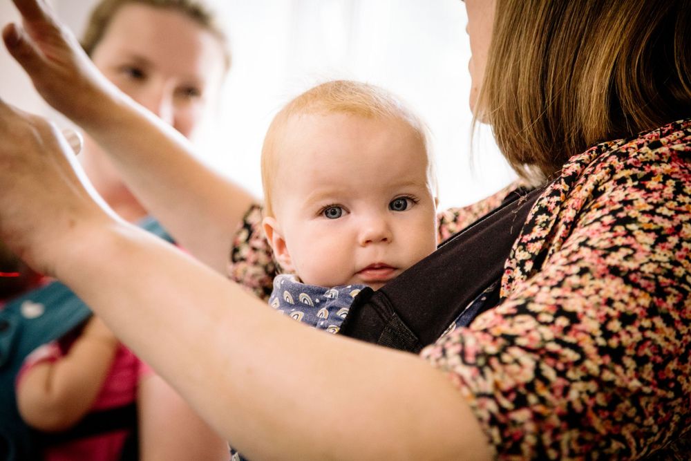 Parent and baby bonding moment while practicing babywearing techniques.