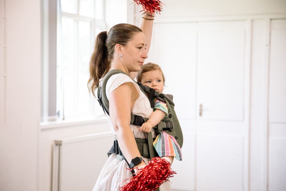 Energetic dance movement captured during a babywearing fitness class.