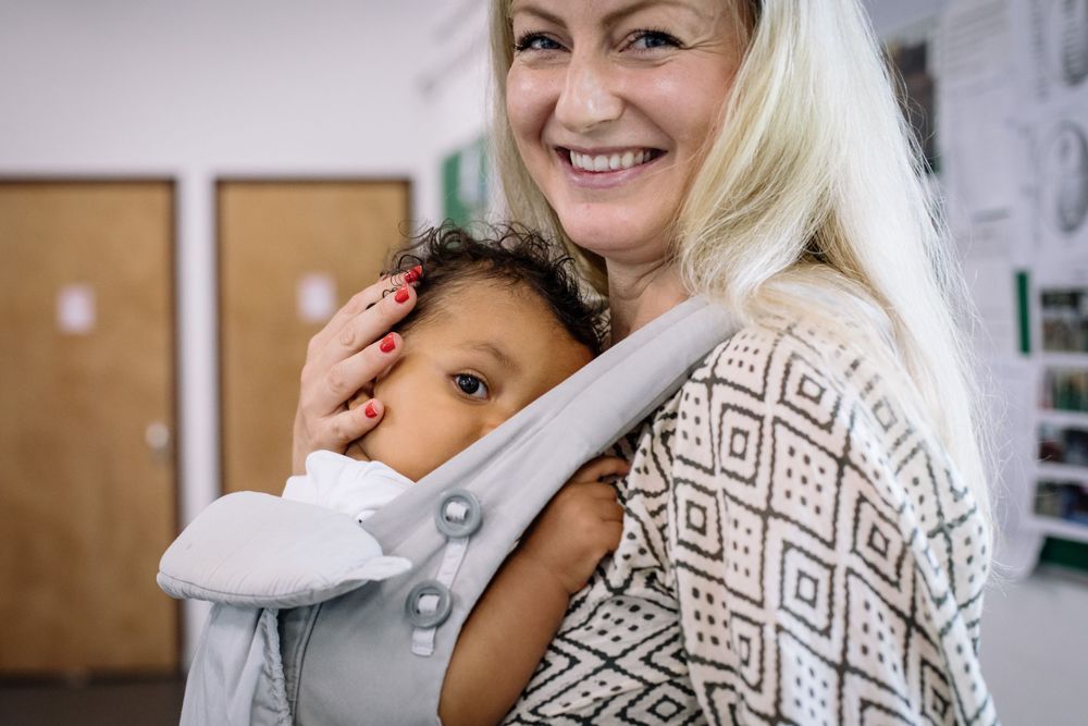 Caregiver and child sharing a tender moment while using a structured baby carrier.
