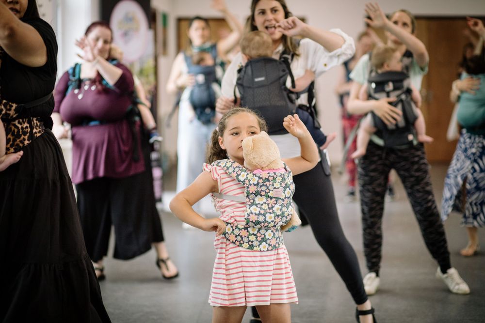 Young child dancing in floral top and striped skirt during group dance class.