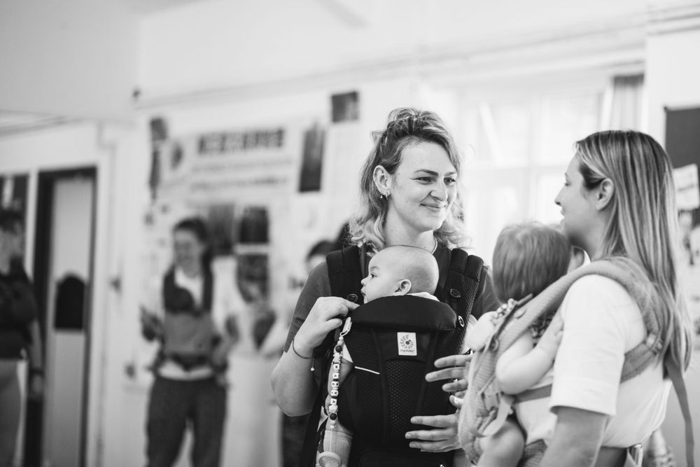 Parents with babies in carriers gather during a parent-child fitness class.