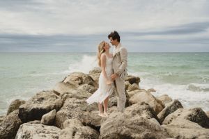 Bride and Groom gazing at each other on some rocks at a beach