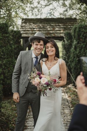 Wedding couple sharing joyful moments in a garden setting with stone walls and greenery.