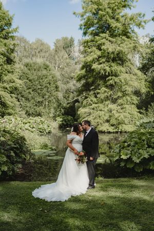 Wedding couple sharing an intimate moment in a lush green garden setting.