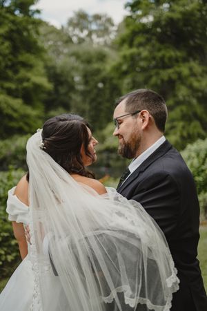 Wedding couple embracing as bride's veil flows dramatically in the breeze.