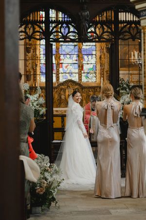 Wedding ceremony in a church with stained glass windows and elegant floral decorations.