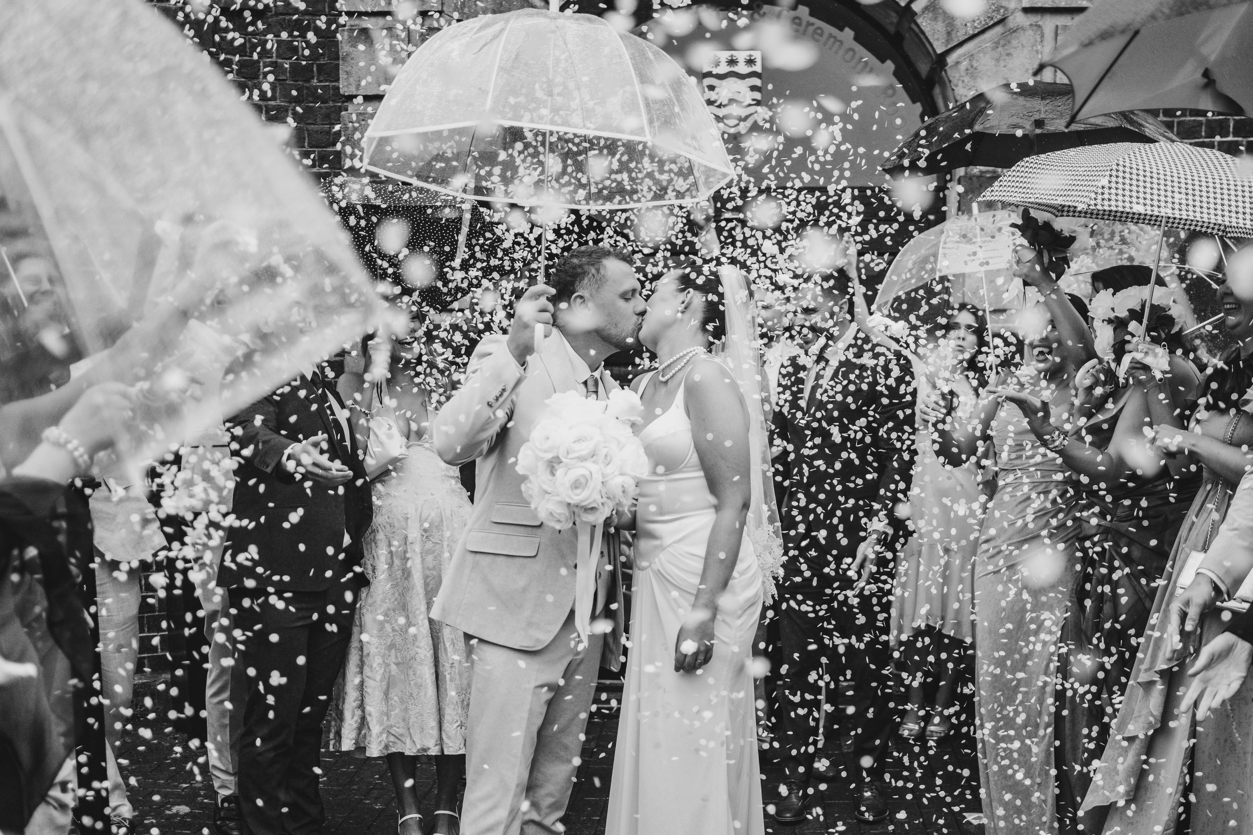 Wedding celebration with guests throwing confetti in a joyous outdoor moment.