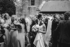 Black and white photo of wedding guests celebrating during an outdoor ceremony.